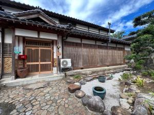 a house with a fence and a stone yard at はたご屋ちゅうべ in Taki