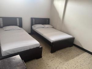 two beds in a small room withermottermott at Astoria Hotel Confortable in Pitalito