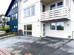 a white house with a balcony and a parking lot at Modern And Cozy Apartment in Tórshavn