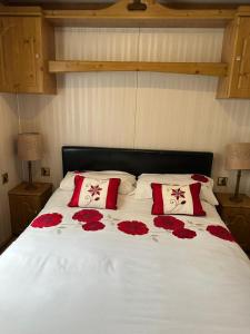 a bed with red roses on it with two pillows at 77 Glenfinart Caravan Park in Dunoon