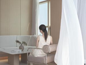 a woman sitting in a chair looking out the window at UH Suite The Haeundae in Busan