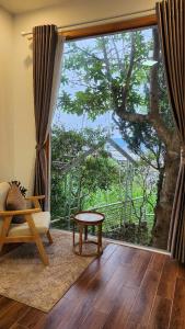 un salon avec une grande fenêtre et une table dans l'établissement 3 Tầng Mây Homestay & Coffee, à Xuân Thọ