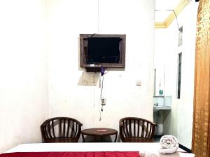 a room with a table and two chairs and a tv at RedDoorz at Hotel Huni Raya Bromo in Pasuruan