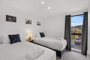 a bedroom with two beds and a window with a view at Skyliine Serenity in Wanaka