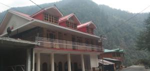a large red building with a mountain in the background at Hotel Ganga view & restaurant in Gangnāni