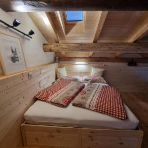 a bed in a wooden cabin with two pillows on it at Bed&Breakfast La Sctalèta in Mesocco