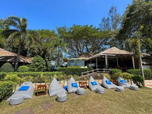 eine Gruppe von Strandstühlen und Tischen auf dem Rasen in der Unterkunft Twin Bay Resort Koh Lanta in Ko Lanta