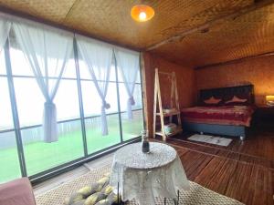 a bedroom with a bed and a table and windows at ASA Private Homestay - บ้านนายพราน แนววินเทจ in Ban Huai Khai