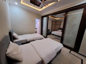 a room with two beds and a window at Pinewood Guest House, Islamabad in Islamabad