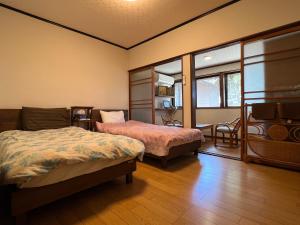 a room with two beds and a couch and windows at はたご屋ちゅうべ in Taki