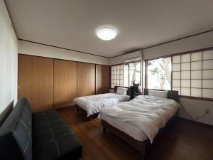 a bedroom with two beds and a couch and a window at はたご屋ちゅうべ in Taki