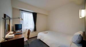 大分市にあるa.Suehiro Hotelのベッドと机、テレビが備わったホテルの部屋