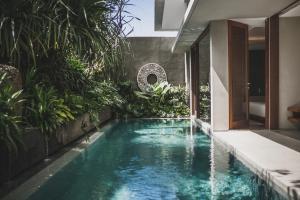 an infinity pool in a house with plants at Blossom Eco Luxe Villas by Ekosistem in Canggu