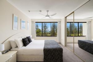 a white bedroom with a bed and a ceiling fan at South Pacific Plaza - Official in Gold Coast +96 photos