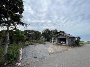 a smallshed with a car parked next to a road at はたご屋ちゅうべ in Taki