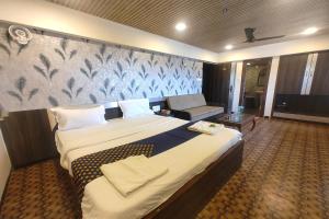 a hotel room with a large bed and a couch at Harmony Inn in Mahabaleshwar