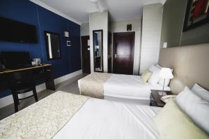 ブエノスアイレスにあるKer Urquiza Hotelのベッド2台とデスクが備わるホテルルームです。