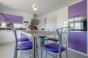 una cocina con armarios morados y una mesa con sillas moradas. en L'annexe, en Saint-Hilaire-sous-Romilly