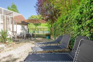 Un grupo de bancos negros en un patio con un paraguas en L'annexe, en Saint-Hilaire-sous-Romilly