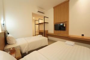 a hotel room with two beds and a flat screen tv at Evertree Hotel in Balikpapan