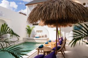 a pool with chairs and a table with a straw umbrella at Antana Hotel in Canggu