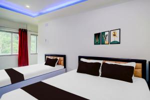 two beds in a room with white walls and red curtains at Hotel O The Silver Stone in Guwahati
