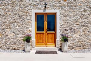 Una puerta de madera en un edificio de piedra con dos jarrones. en Casa Škitaconka, en Koromačno
