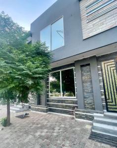 费萨拉巴德Elysian Nest 2BR Apartment Abdullah Gardens的一栋房子前面有一棵树