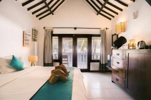 ein Teddybär sitzt auf einem Bett in einem Schlafzimmer in der Unterkunft Tír na nÓg Beachfront Resort in Gili Trawangan