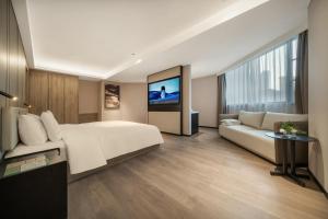 a bedroom with a large white bed and a couch at Atour Hotel Chunxi Road Chengdu in Chengdu