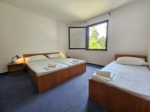 two beds in a room with a window at Mala Luka - Omiš, Beach Resort in Stanići