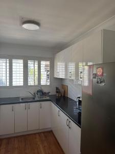 a kitchen with white cabinets and a black counter top at Brighton Beach Villa Scarborough in Perth