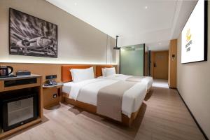 a hotel room with two beds and a television at Guangzhou Baiyun Airport COCO Hotel T2 Terminal Store Canton Fair Free Shuttle Bus in Huadu
