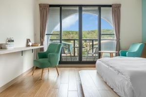 a bedroom with a bed and two chairs and a large window at 北極熊旅店 in Xiaoliuqiu