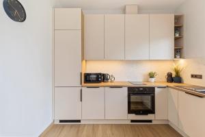 a kitchen with white cabinets and a clock on the wall at Niwaki Sodai No 2 by URBAN RENT in Vilnius +22 photos