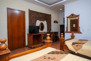 ein Schlafzimmer mit zwei Betten und einem Fernseher und einem Spiegel in der Unterkunft Urbanview Omah Eka Santi by RedDoorz in Yogyakarta