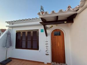 a white house with a wooden door and window at Casa NURA in Son Bou