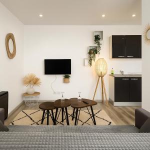 a living room with tables and a tv on a wall at Le Vosgien - Hyper center - Calme - Wifi - Spacieux in Épinal