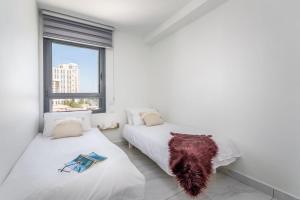 two beds in a white room with a window at Eshel Suites Even Israel in Jerusalem