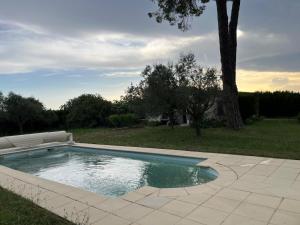 a swimming pool in a yard with a tree at Maison familiale avec Mazet et grande piscine Uzès in Uzès