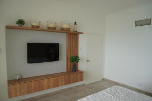 Una sala de estar con un televisor de pantalla plana en una pared. en Hotel Colon Salinas 2 bedroom Oceanview apartment, en Salinas