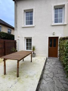 a wooden picnic table in front of a house at Jolie Maison Proche Tous Commerces in Agneaux