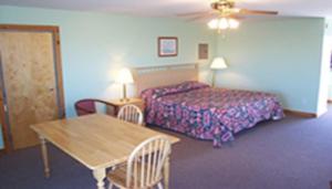 a hotel room with a bed and a table at Blue Sea Motor Inn in North Truro
