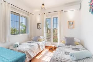 two beds in a room with two windows at Finca Lavinia in Alhaurín el Grande