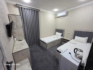 a small room with two beds and a tv at Anor Hotel Navoiy in Navoi
