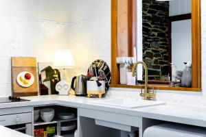 - un comptoir de cuisine avec un évier et un miroir dans l'établissement Coachman's Cottage Glenelg, à Glenelg
