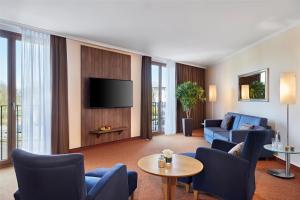 a living room with a couch and a tv at Lindner Hotel Leverkusen BayArena, part of JdV by Hyatt in Leverkusen