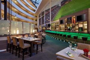 ein Restaurant mit Tischen und Stühlen und einer grünen Wand in der Unterkunft The Curve Hotel BayArena in Leverkusen