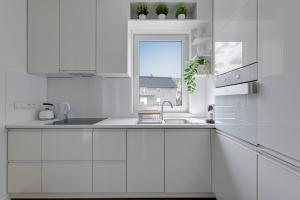 a white kitchen with a sink and a window at APARTAMENT BLISKO TRÓJMIASTA I KASZUB, 20 minut komunikacją miejską do centrum Gdyni in Rumia