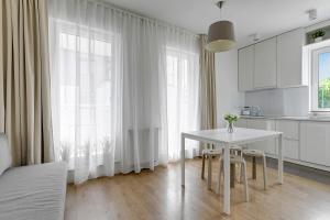 a white kitchen with a white table and a window at APARTAMENT BLISKO TRÓJMIASTA I KASZUB, 20 minut komunikacją miejską do centrum Gdyni in Rumia +10 photos
